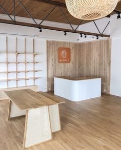 an empty room with wooden flooring and white tables in the center, surrounded by bamboo screens