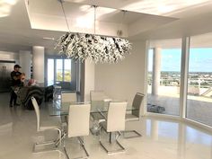 a dining room table with white chairs and a chandelier hanging from the ceiling