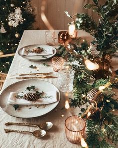 the table is set for christmas dinner with pine cones