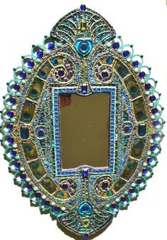 an ornate mirror with blue and green beads on the edges, hanging from a wall