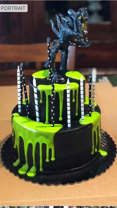 a green and black cake with candles on it