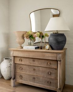 a dresser with a mirror, lamp and vase on top