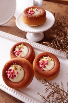 three small pastries on a white plate with sprinkles and pink flowers