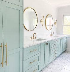 a bathroom with blue cabinets and two round mirrors