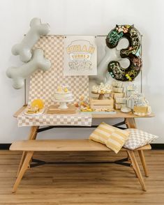 a table topped with lots of cakes and desserts next to a giant letter shaped balloon