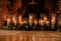 many candles are lit in front of a fireplace