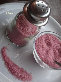 two jars filled with pink powder on top of a white plate next to a spoon