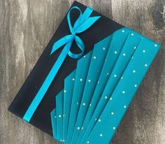 a blue gift box wrapped in black paper with white polka dots and a turquoise ribbon