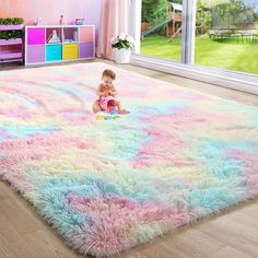 a baby is sitting on the floor in front of a large rug with pastel colors