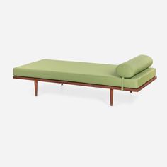 a green daybed sitting on top of a white floor next to a wooden frame