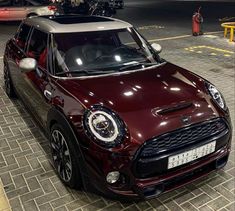 a maroon mini cooper parked in a parking lot