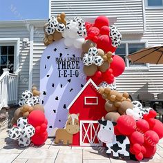 an inflatable barn with balloons and farm animals on the front yard for a birthday party