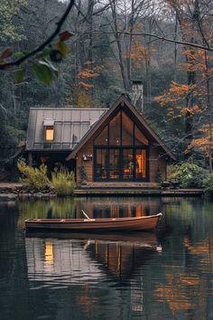 a small boat floating on top of a lake next to a wooden cabin in the woods