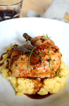 a white plate topped with meat covered in gravy and mashed potatoes next to a glass of wine