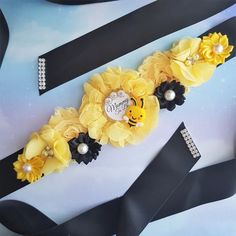 a yellow and black ribbon with flowers on it