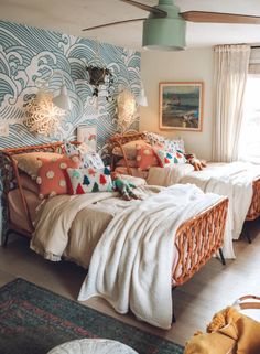 two beds in a room with blue and white wallpaper on the walls, one is made from wicker