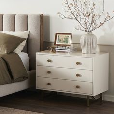 a white dresser sitting next to a bed in a bedroom