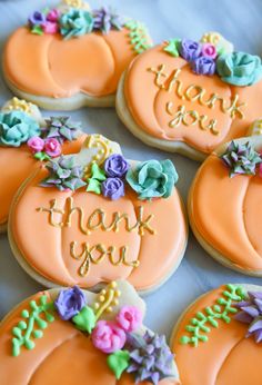 decorated pumpkin cookies with thank you written on the top and flowers at the bottom, sitting on a table