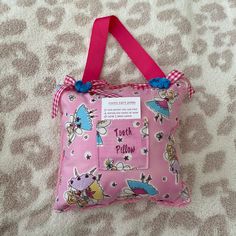 a pink and white pillow on top of a bed covered in animal print with a pink ribbon