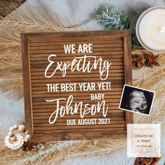 a wooden sign that says we are expecting the best year yet, with an image of a baby