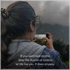 a woman taking a photo with her cell phone while standing in front of the mountains