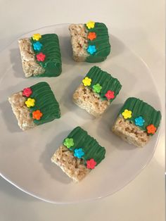 four pieces of rice krispy treats on a white plate with green leaves and flowers