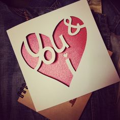 a card with the word i love you cut out of paper on top of it