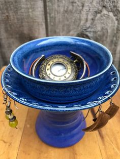 a blue vase with three rings on it sitting on top of a wooden table next to a wall