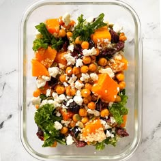 a salad in a glass dish on a marble counter top with oranges, feta cheese and lettuce