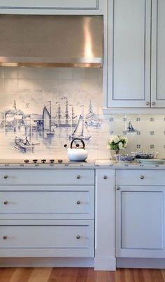 a kitchen with white cabinets and an island in front of the stove top is decorated with sailboats