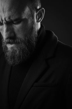 a man with a beard wearing a suit and looking at his cell phone in the dark