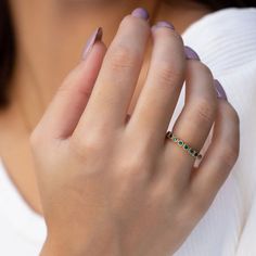 a woman wearing a gold ring with green stones