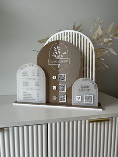 two headstones on top of a white cabinet with flowers in the corner and an american cemetery sign