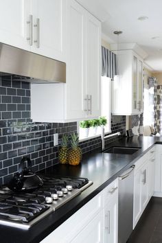 a kitchen with white cabinets and black counter tops is pictured in this image, there are pineapples on the stove top