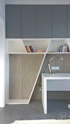 a white desk sitting under a window next to a book shelf