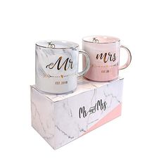 two coffee mugs sitting on top of each other in marble boxes with the words mr and mrs printed on them