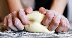 a person kneading dough on top of a table with their hands over it