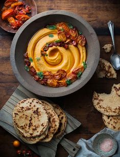 a bowl filled with hummus next to some pita bread and other food items