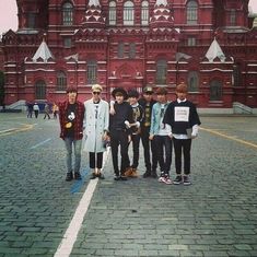 a group of young men standing in front of a red building with a clock tower