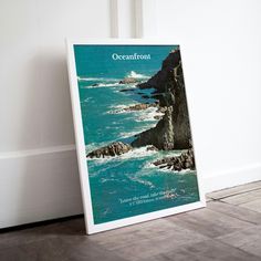 an oceanfront poster is on the floor next to a white wall and wooden floors