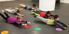 several children laying on the floor playing with frisbees