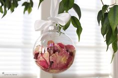 a glass ornament hanging from a tree filled with pink flowers and greenery