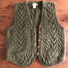 a green sweater vest sitting on top of a wooden floor