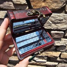 a hand holding a small red and black case