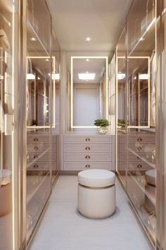 an empty walk in closet with lots of drawers and mirrors on the walls, along with a stool