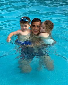 a man and two children swimming in a pool with clear blue water at the bottom