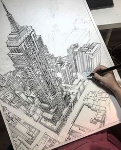 a person is drawing a cityscape on paper