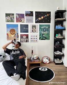 a man sitting on top of a bed next to a wall covered in pictures and posters