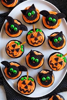 halloween cupcakes decorated with black and orange icing on a white platter