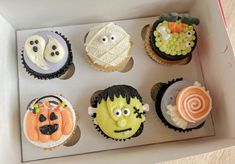 a box filled with cupcakes decorated to look like cartoon characters and faces on them